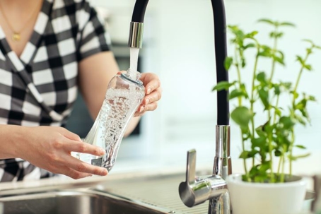 woman filling a bottle from a functioning faucet